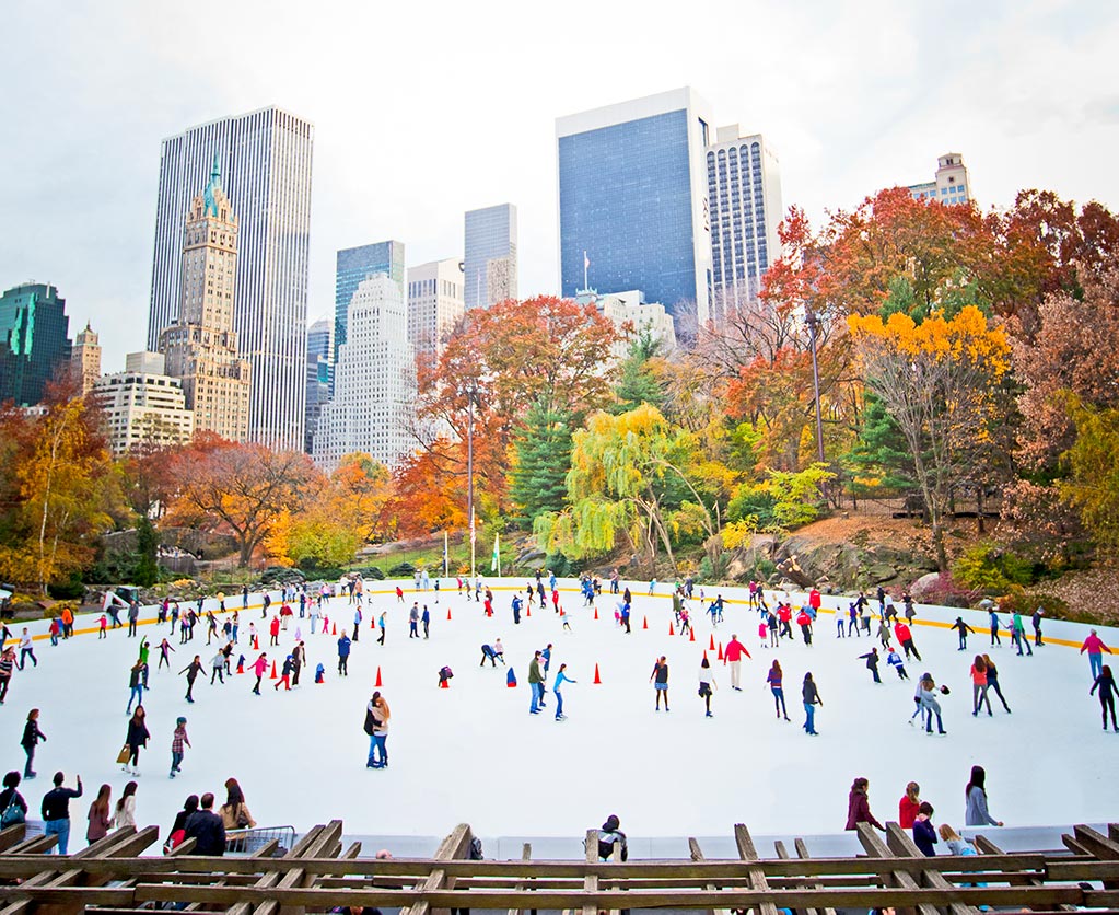 Ice skating in Central Park NYC with late fall color in the trees.