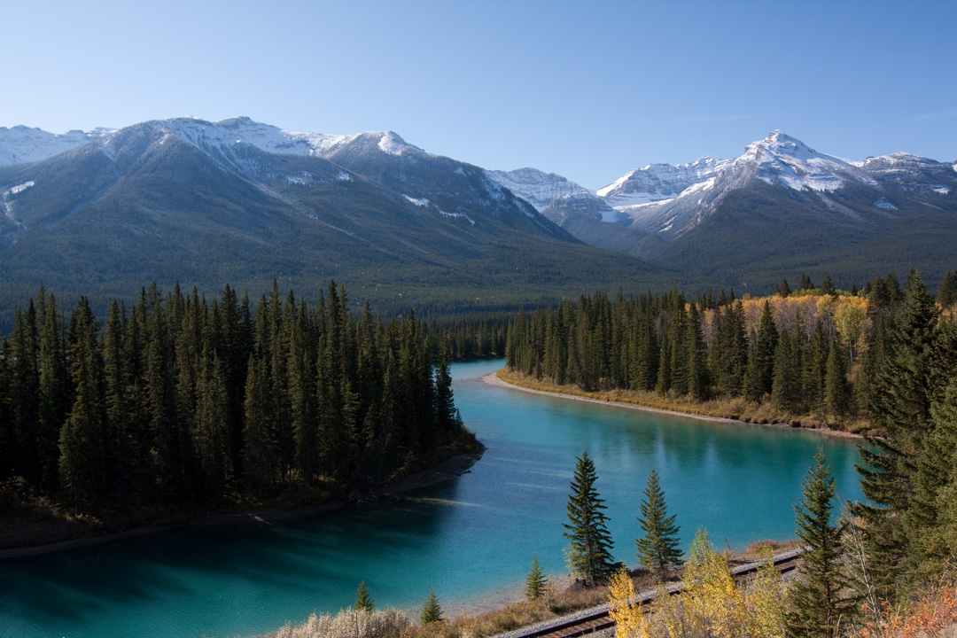 Bow Valley viewpoint with clear blue water, surrounded by trees, and view of mountains.